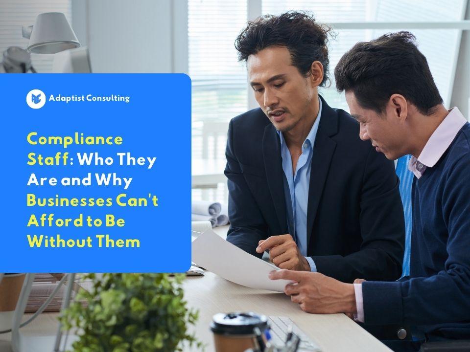 Two business professionals reviewing documents together at an office desk as part of a company's compliance staff process