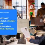 staf IT meninjau dokumen identitas karyawan di depan komputer.