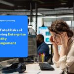 Stressed office worker woman at a computer as an illustration of the fatal risks from ignoring enterprise identity management.