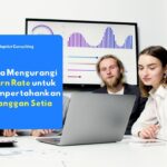 Karyawan yang sedang menganalisis grafik retensi pelanggan dan metrik churn rate pada dasbor sistem di layar monitor komputer.