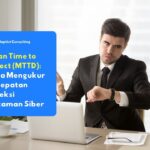 Seorang pengusaha berkemeja yang sedang memeriksa jam tangannya sambil bekerja di depan laptop, menggambarkan betapa pentingnya kecepatan deteksi dalam keamanan siber.