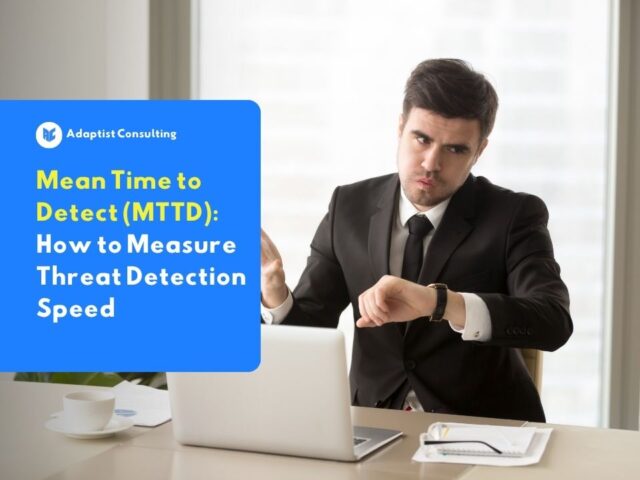 A businessman in a suit checking his watch while working on a laptop, representing the urgency of mean time to detect in cybersecurity.