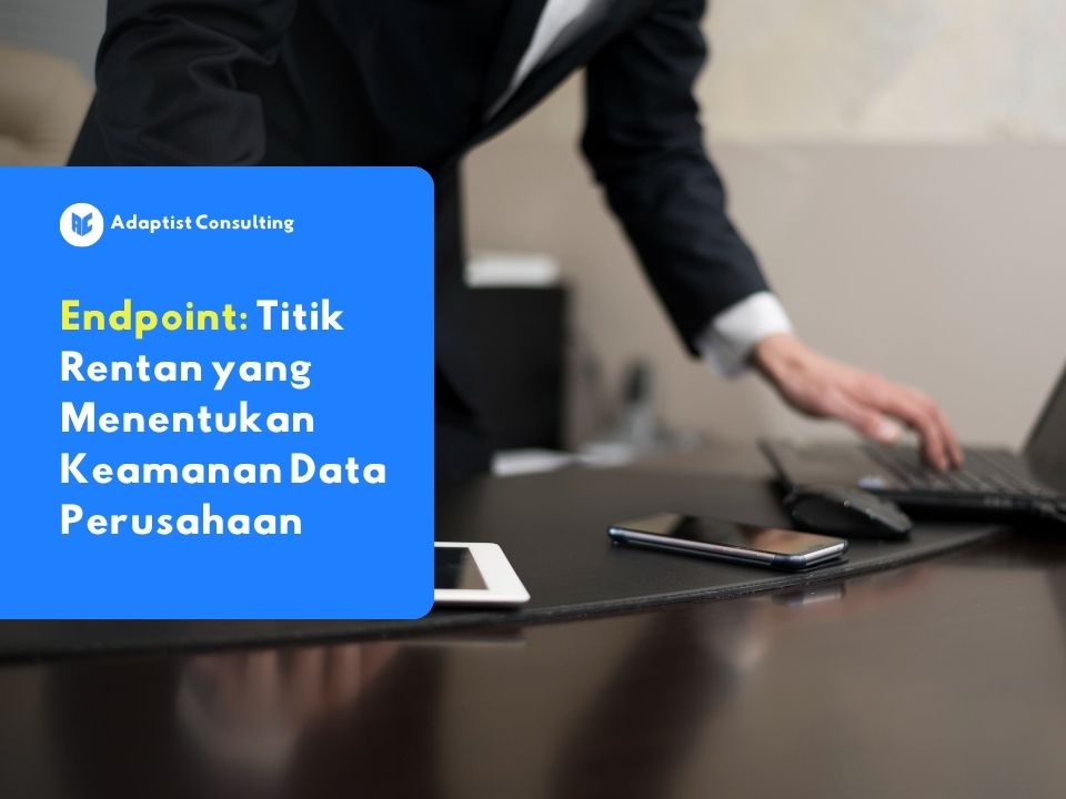 Seorang karyawan mengamati tiga perangkat sekaligus, yaitu laptop, smartphone, dan tablet, yang masing-masing terhubung ke jaringan perusahaan sebagai contoh nyata endpoint dalam lingkungan kerja sehari-hari.
