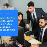 Teknisi IT Support profesional sedang memantau sistem jaringan perusahaan di depan layar komputer di lingkungan kantor modern.
