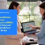 Two IT security professionals analyzing user behavior data on a laptop using User and Entity Behavior Analytics (UEBA) to detect internal threats within an organization.