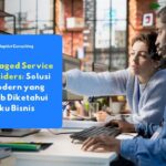 Dua profesional IT sedang memantau sistem bersama di depan komputer, menggambarkan cara kerja Managed Service Provider dalam mendukung operasional bisnis modern.