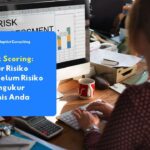 Seorang profesional sedang mengetik di depan komputer yang menampilkan grafik risk assessment.