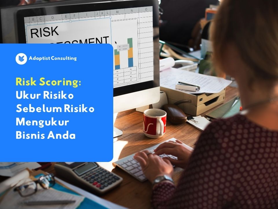 Seorang profesional sedang mengetik di depan komputer yang menampilkan grafik risk assessment.