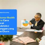 Karyawan yang sedang menganalisis grafik retensi klien pada layar monitor untuk mengevaluasi matriks Customer Health Score perusahaan.