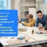 Sekelompok karyawan yang sedang sibuk bekerja menggunakan laptop dan perangkat pribadi di meja kantor, mengilustrasikan potensi terjadinya praktik shadow it.